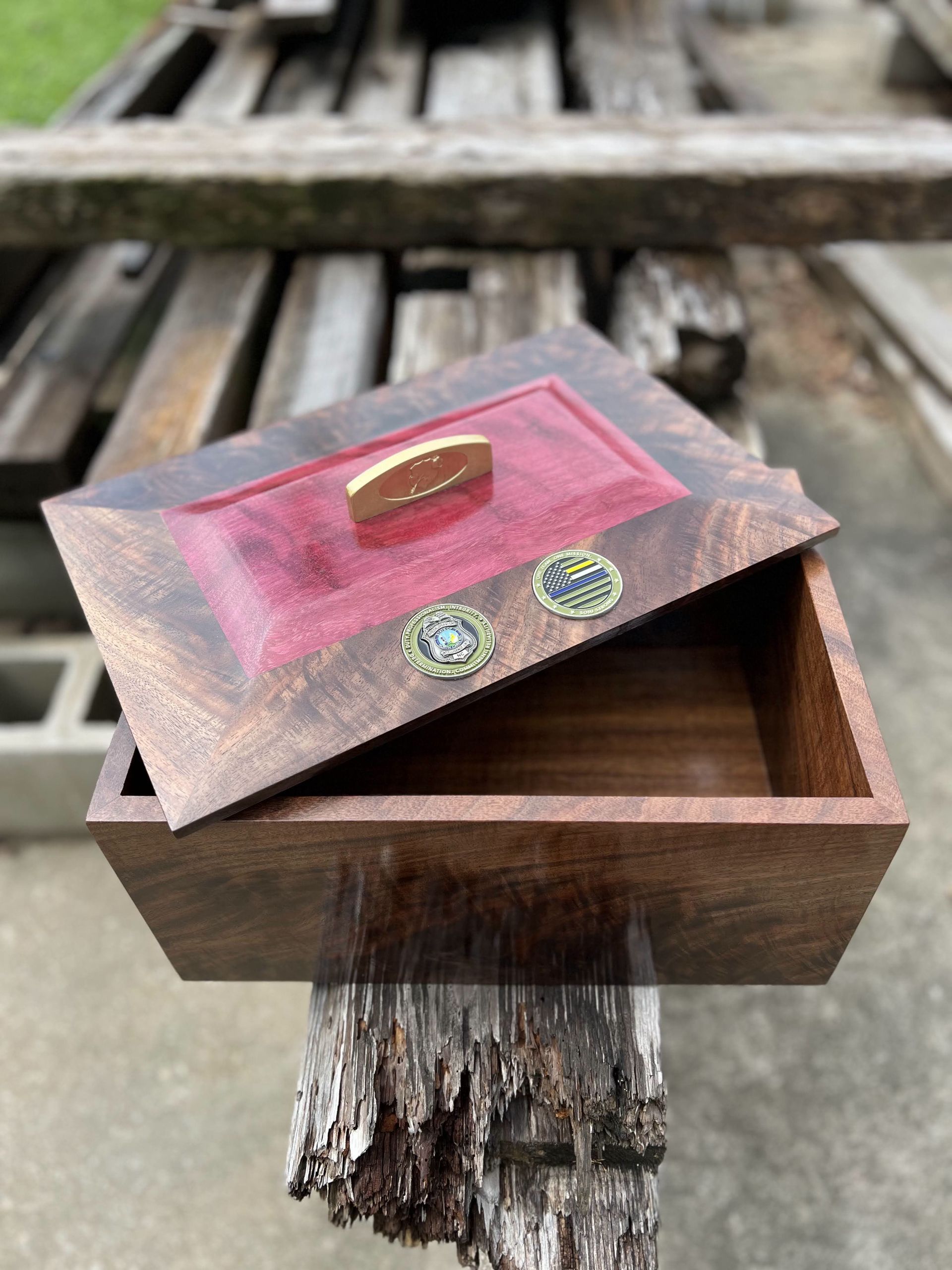 A wooden box with a red lid is sitting on a wooden table.