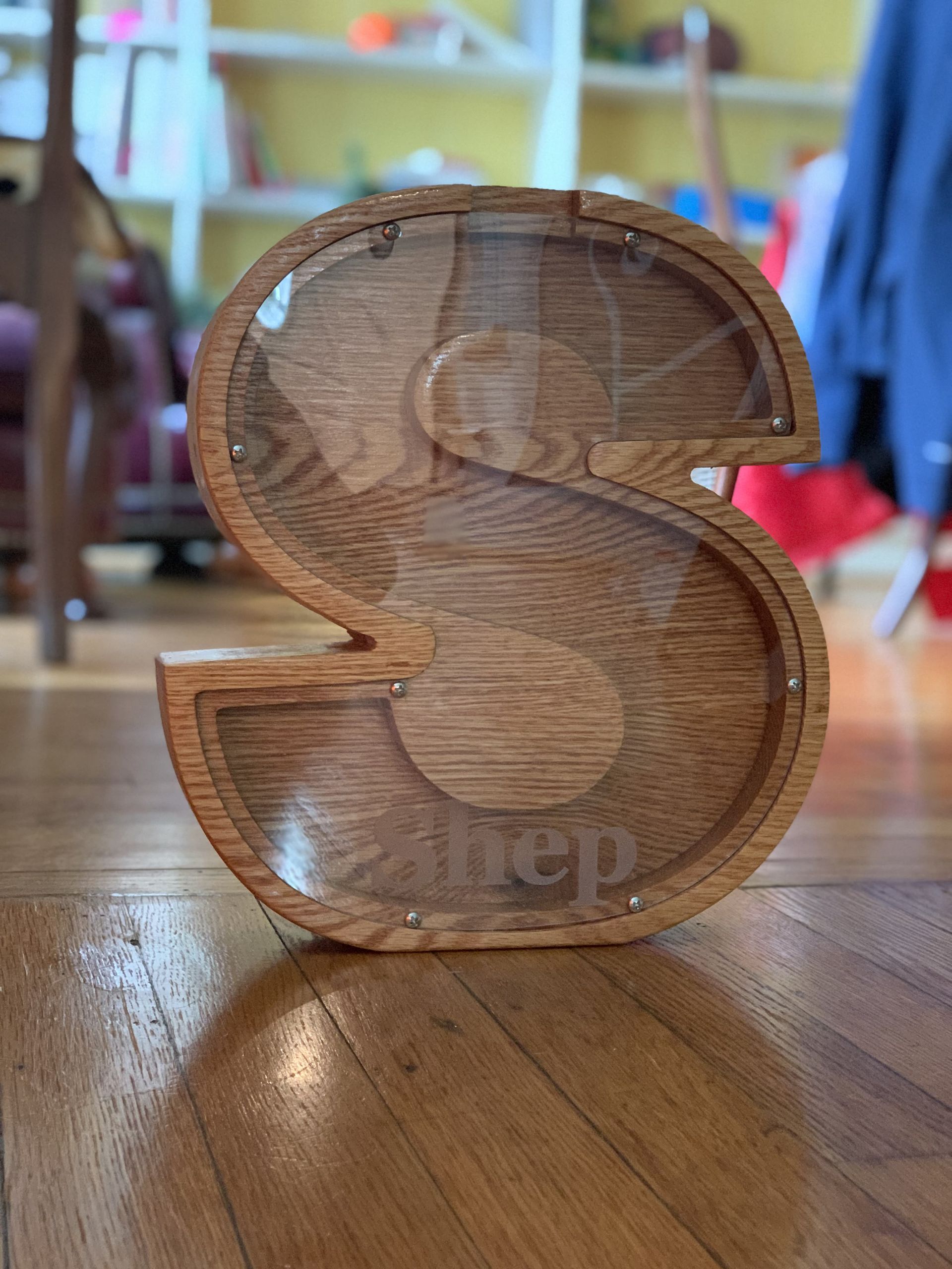 A wooden piggy bank in the shape of the letter s