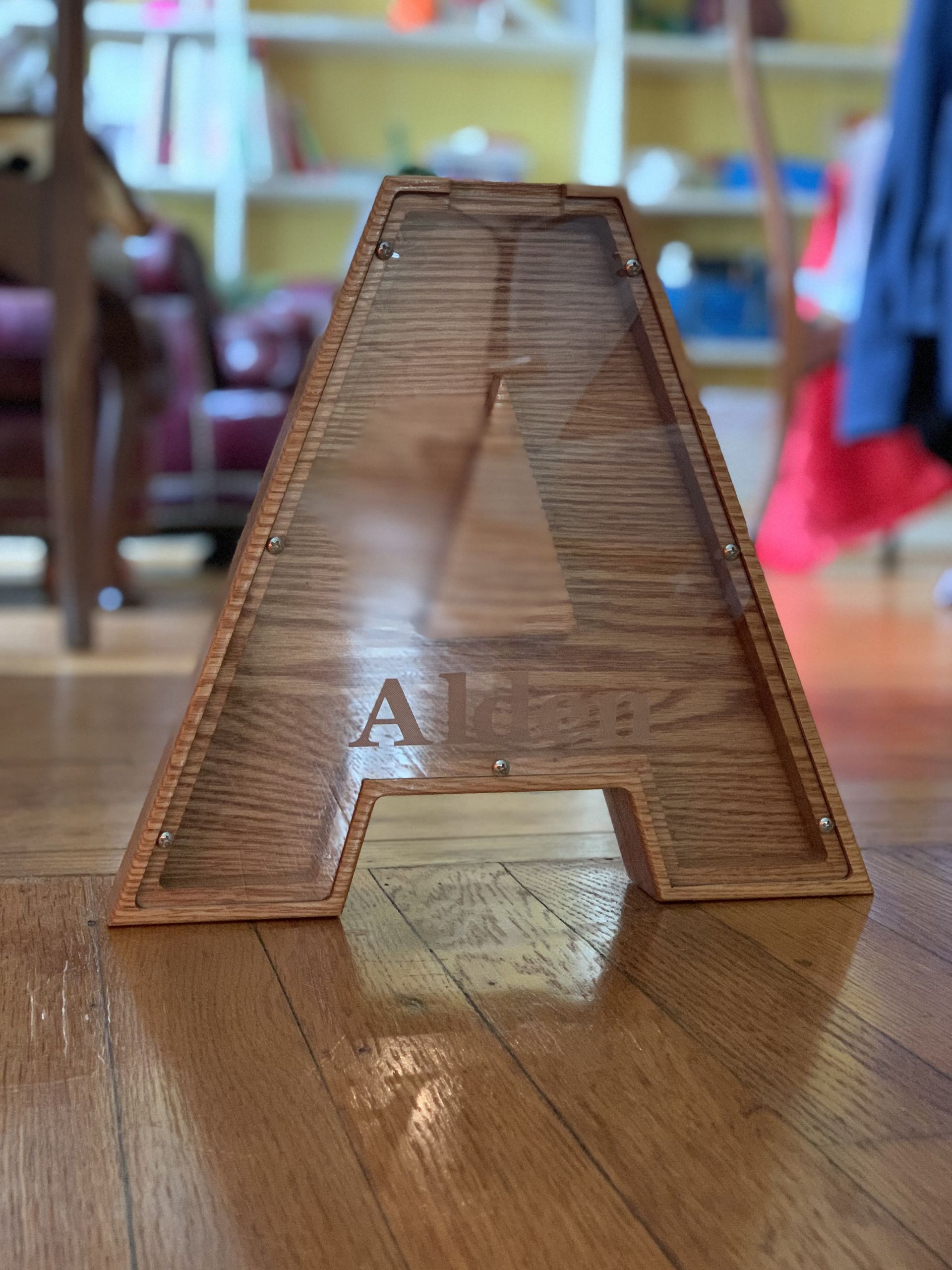 A wooden letter a is sitting on a wooden floor.