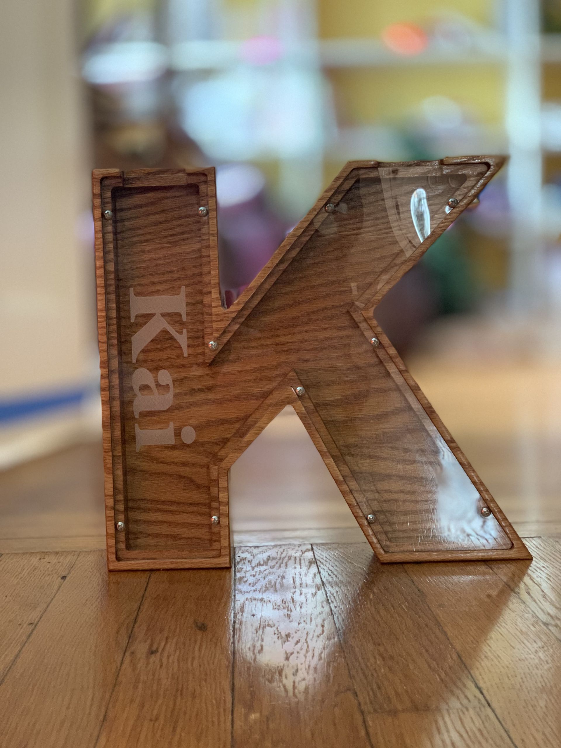 A wooden letter k is sitting on a wooden floor.