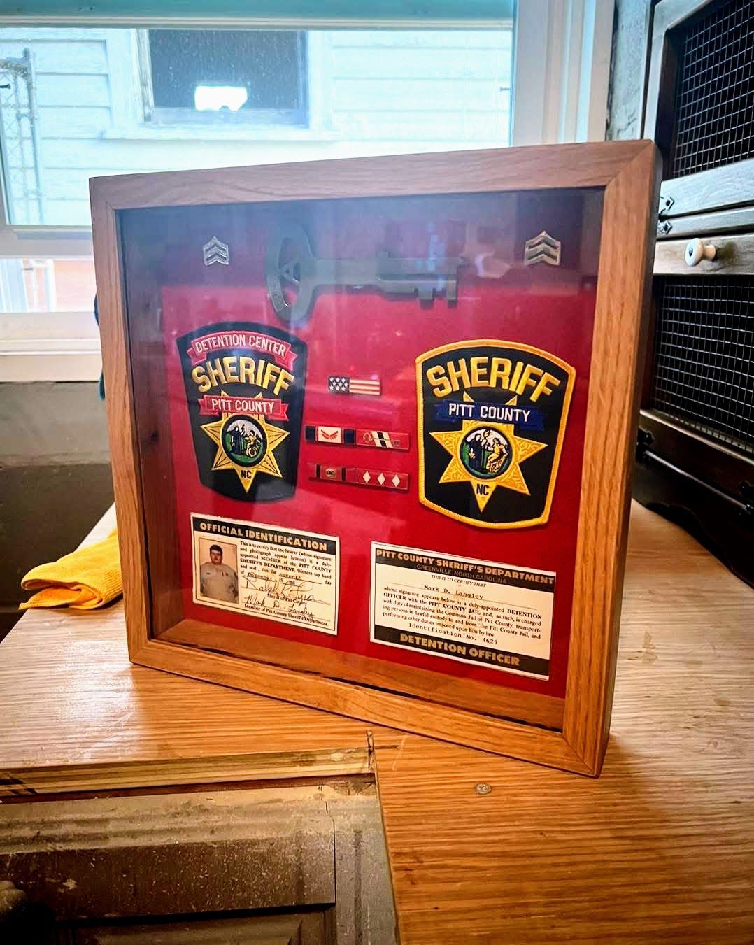 A framed picture of a sheriff 's badge is sitting on a wooden table.