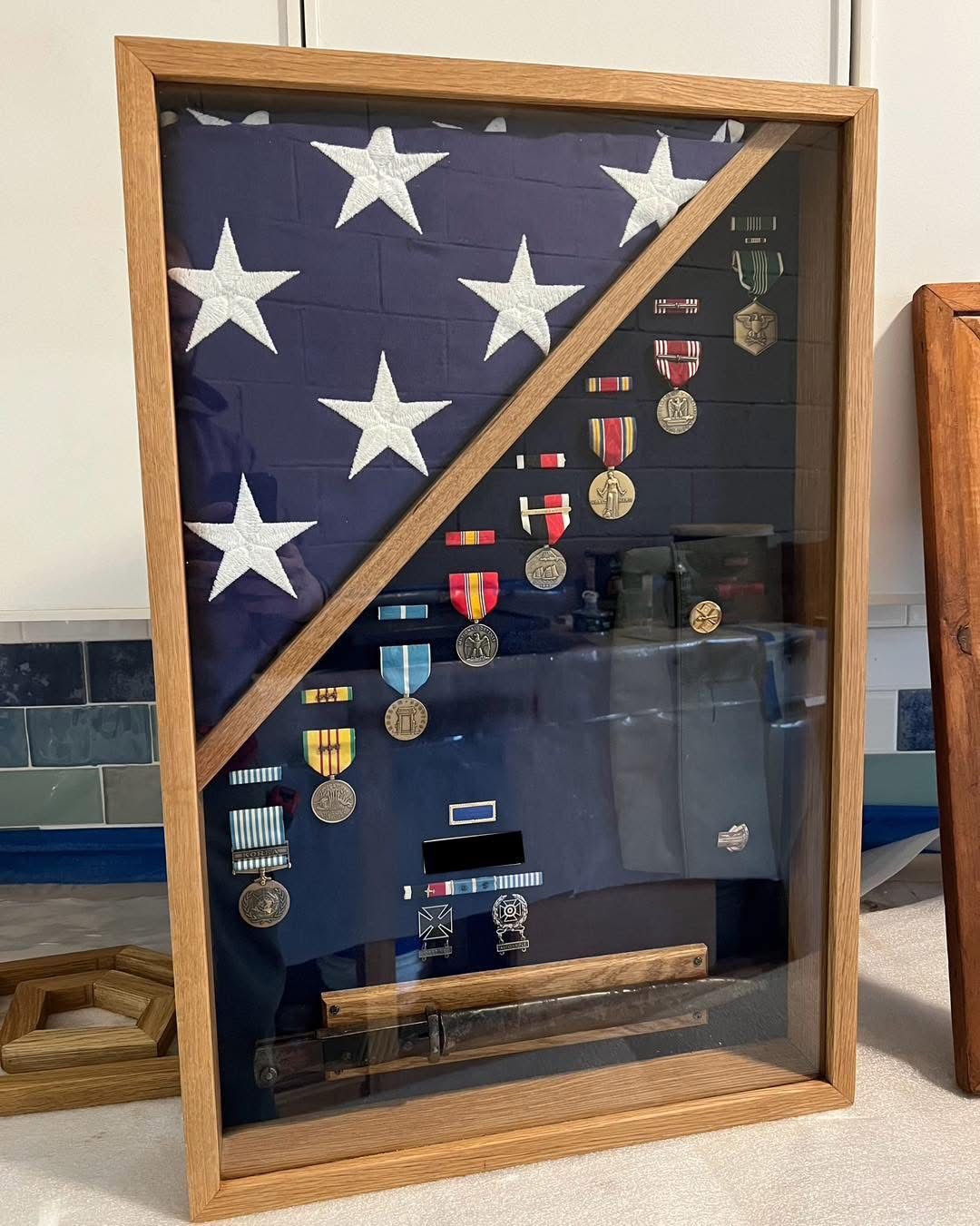 An american flag is displayed in a wooden frame with medals.