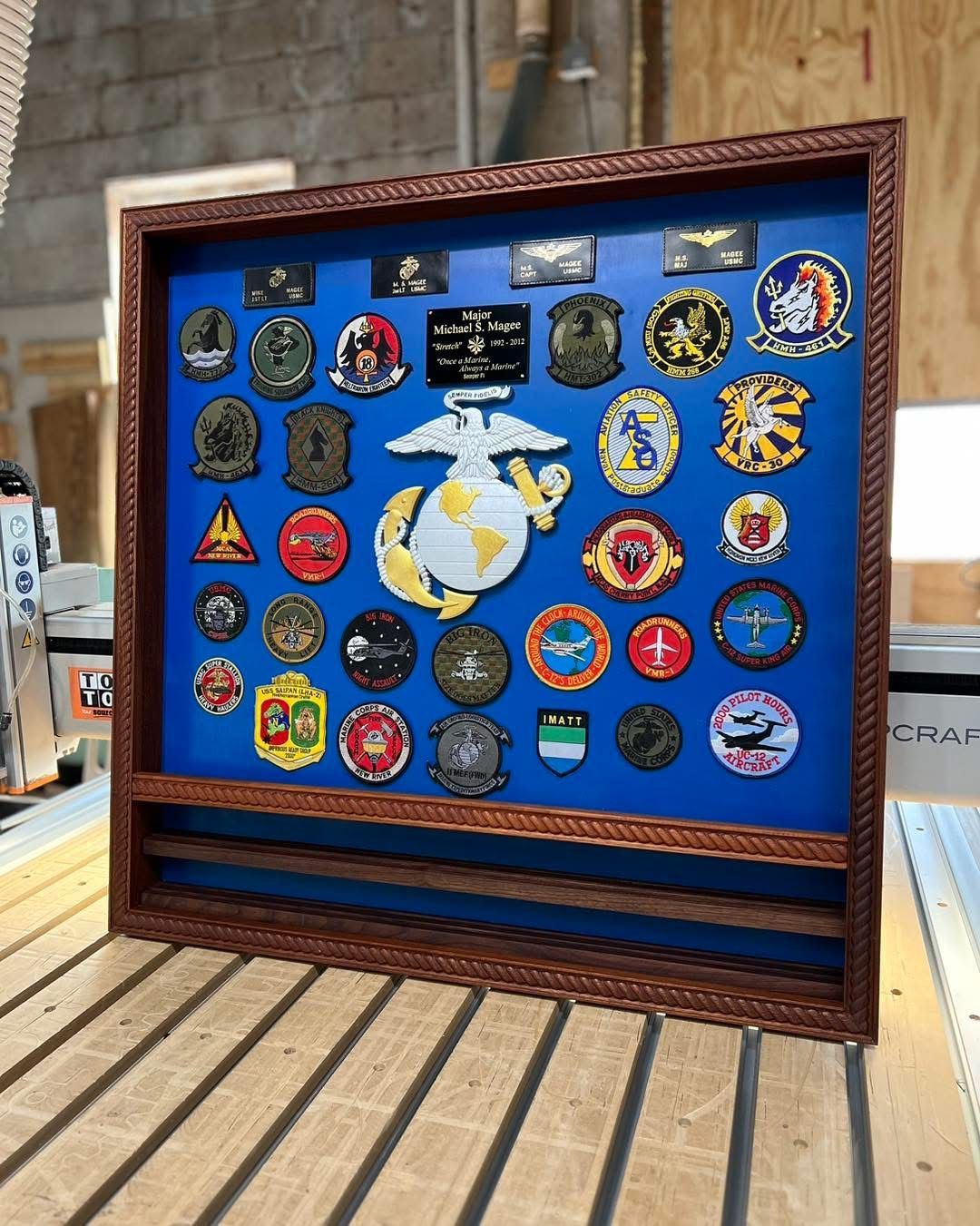 A framed display case filled with military badges on a wooden table.