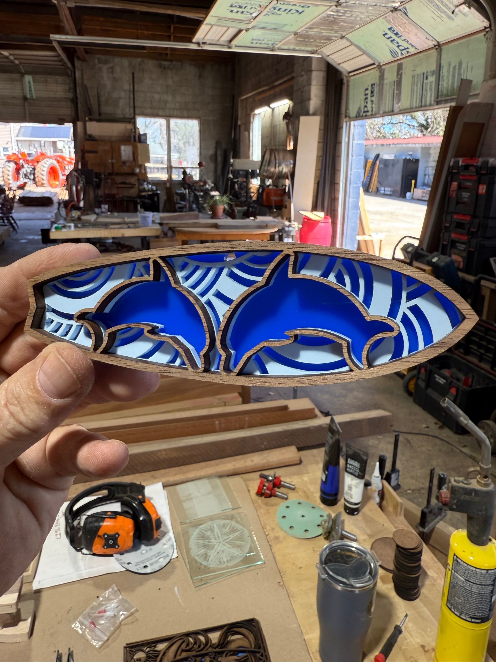 A person is holding a blue and white piece of wood in a workshop.