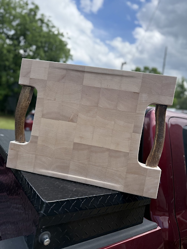 A wooden cutting board with antlers is sitting on the back of a truck.