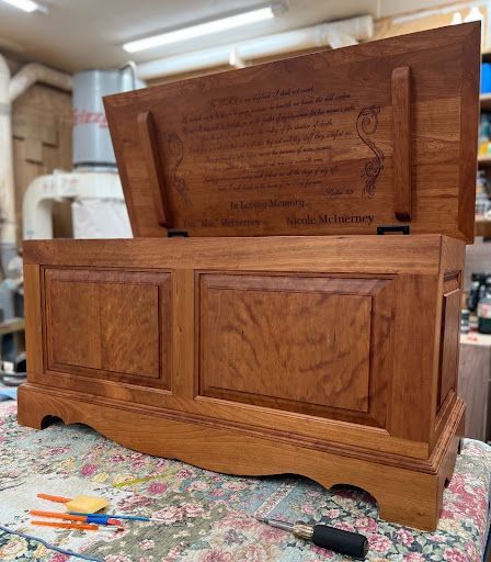 A wooden chest with the lid open is sitting on a table.