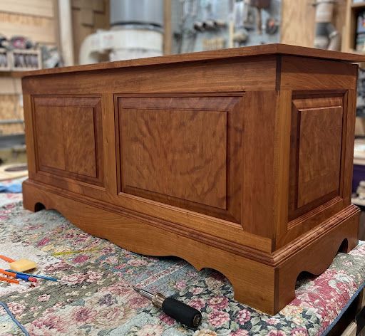 A wooden chest is sitting on a table next to a screwdriver.