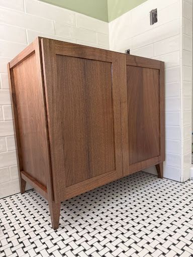 A wooden cabinet is sitting on a tiled floor in a bathroom.