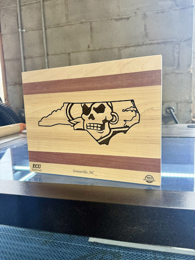 A wooden cutting board with a skull on it is sitting on a table.