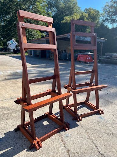 Two wooden chairs are sitting next to each other in a parking lot.