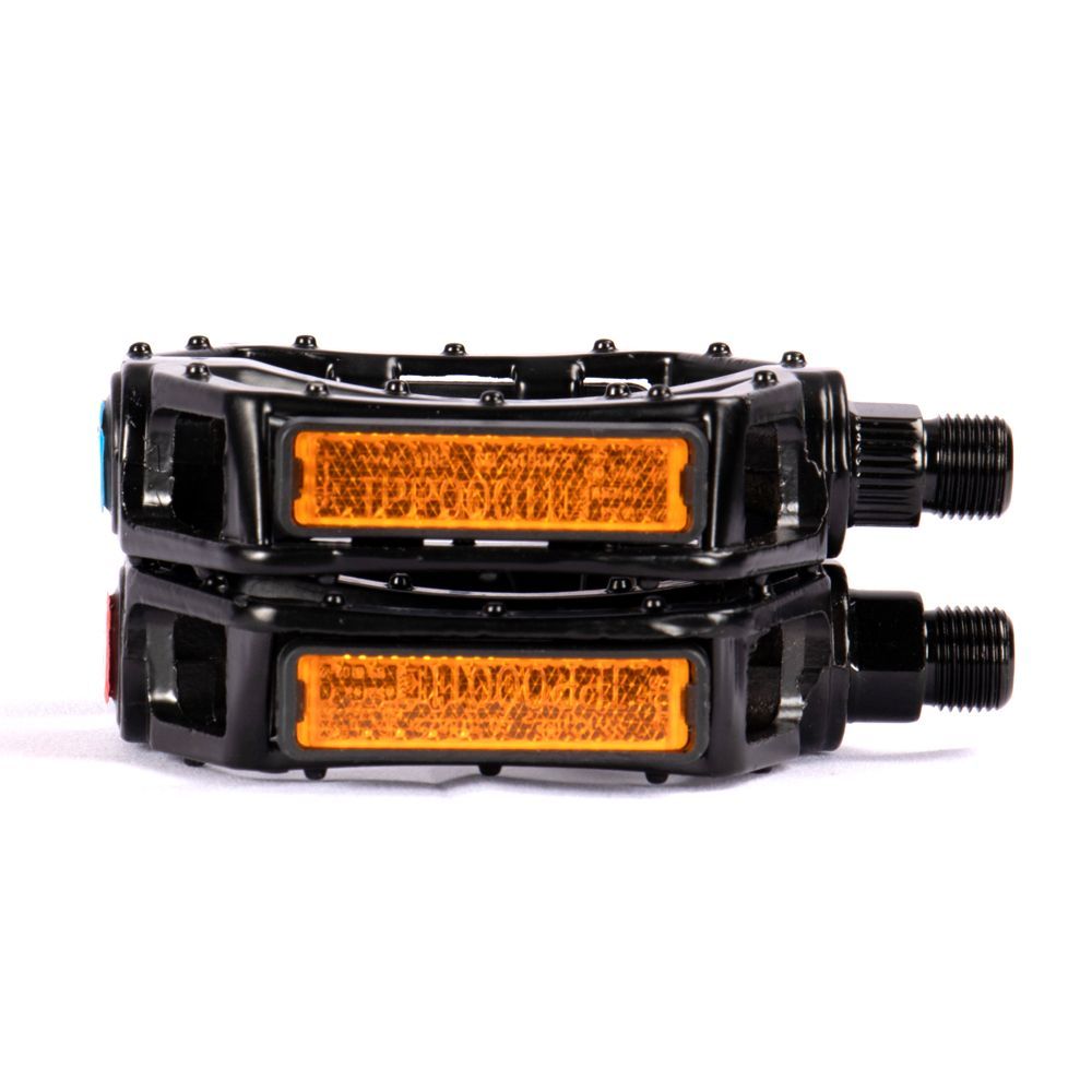 Black bicycle pedals with orange reflectors, stacked on a white surface.