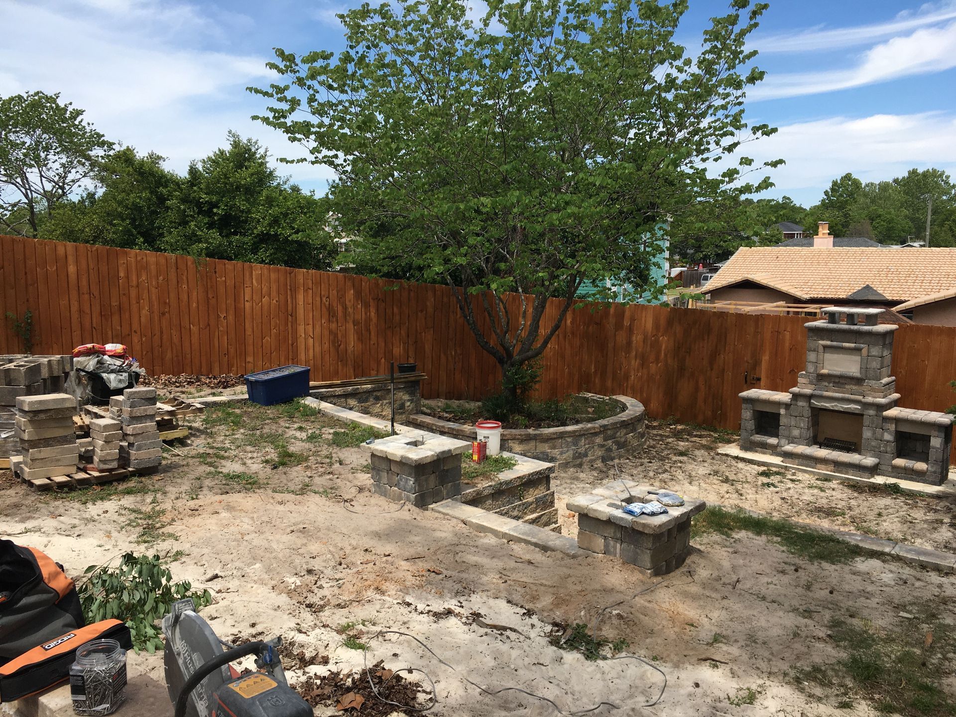 A backyard with a wooden fence and a fireplace.
