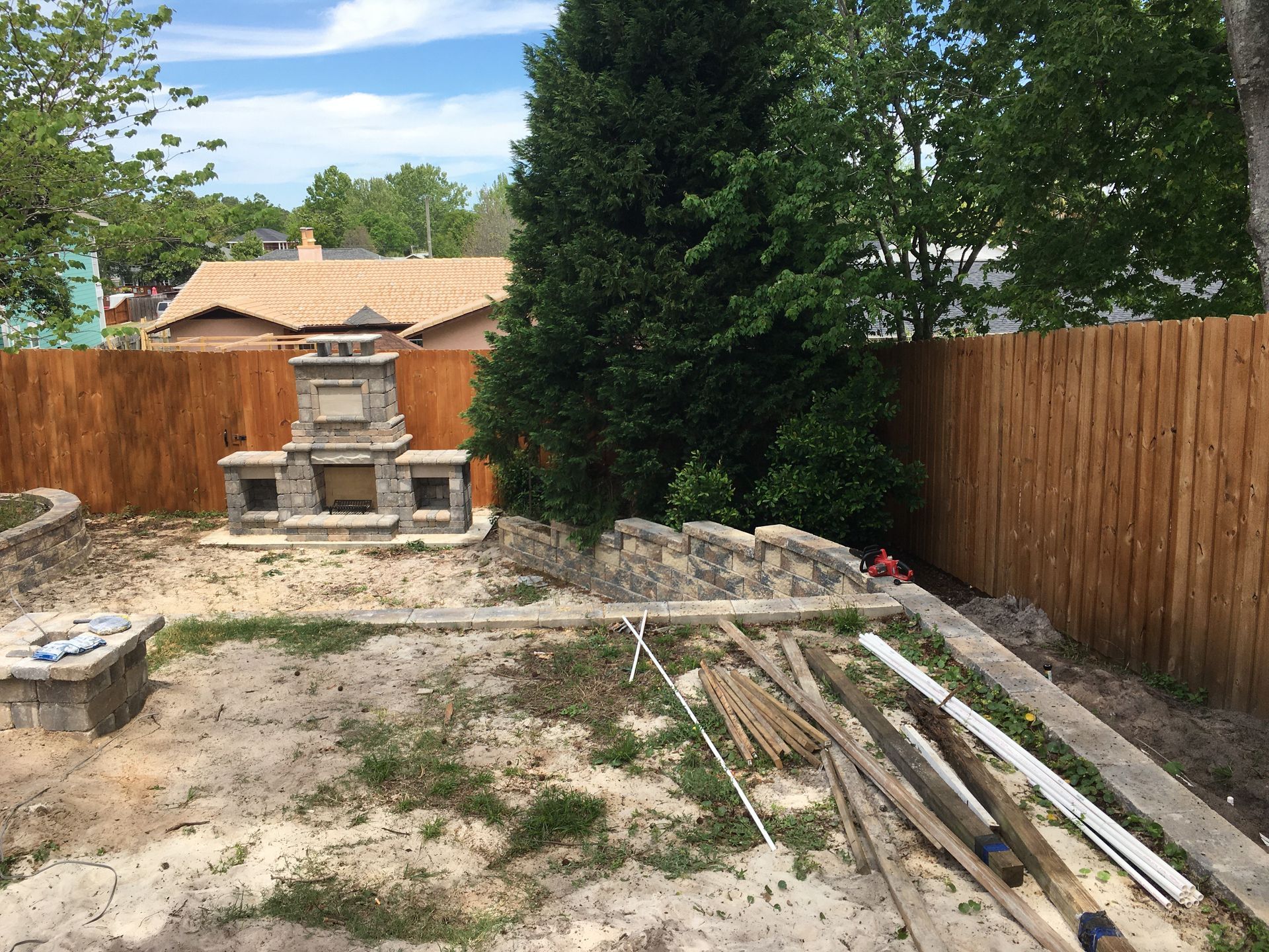 A backyard with a fireplace and a wooden fence.