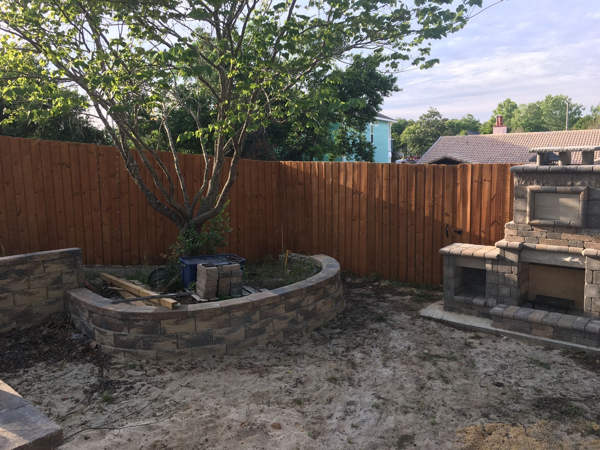 A backyard with a wooden fence and a brick wall.