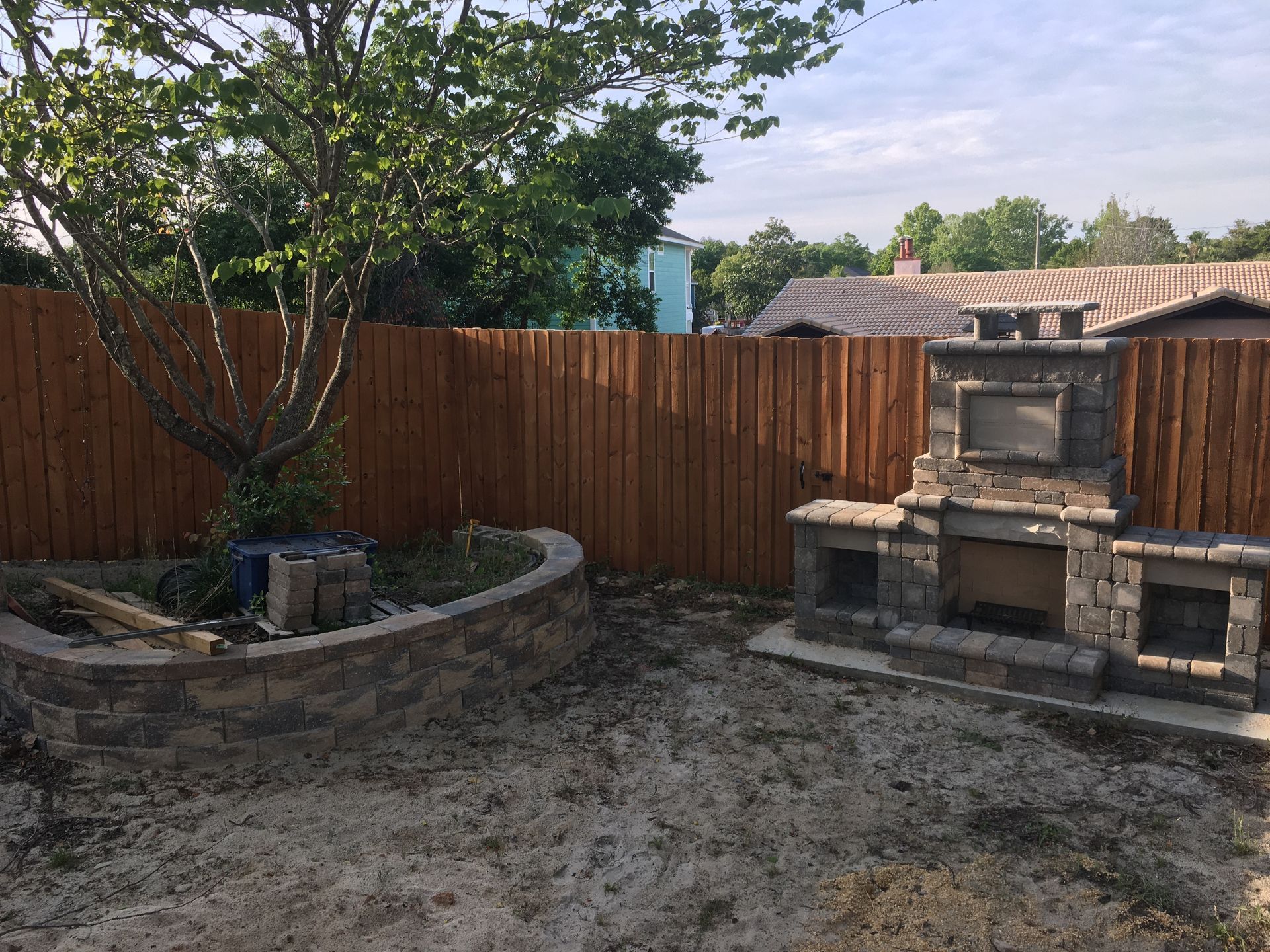 A backyard with a wooden fence and a fireplace.