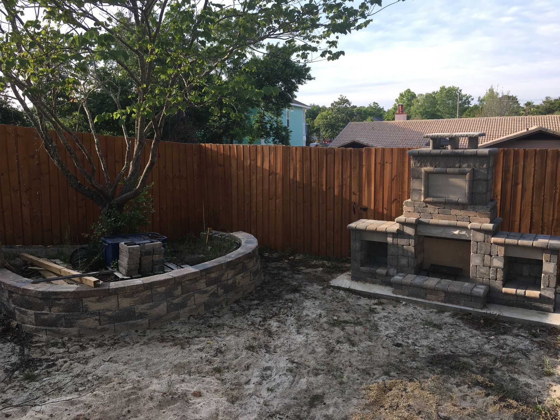 A backyard with a wooden fence and a brick wall.