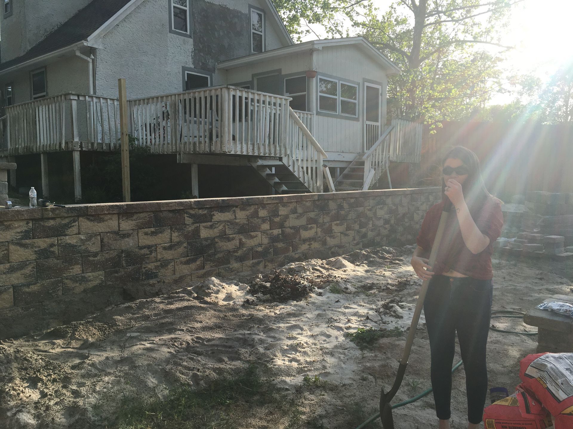 A man standing in front of a house holding a shovel