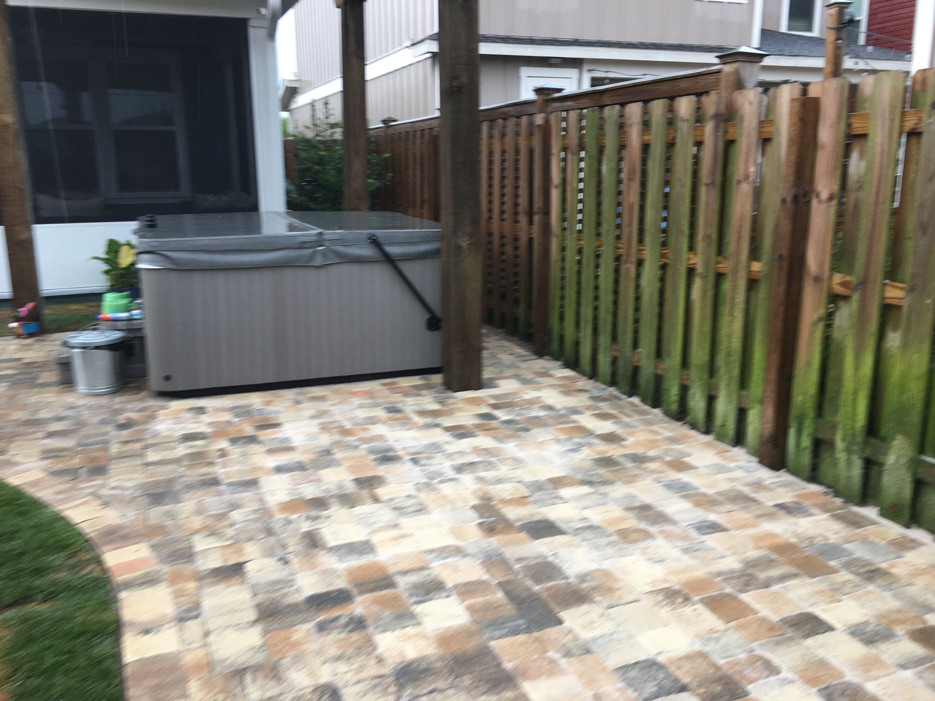 A hot tub is sitting on a patio next to a wooden fence.