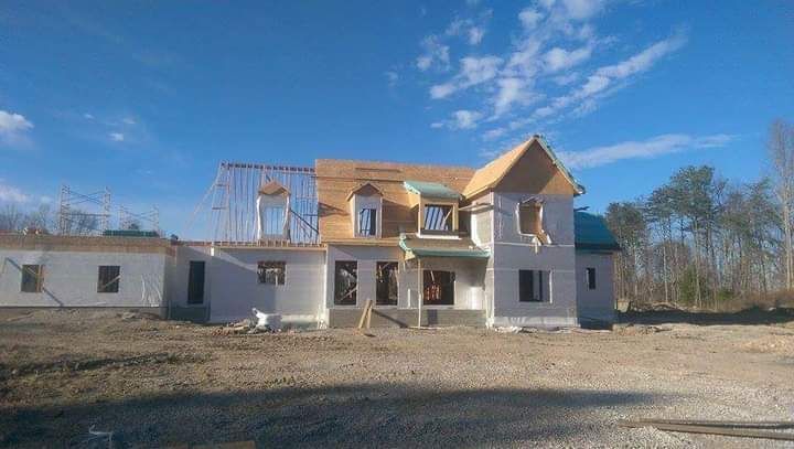 A large house is being built in the middle of a dirt field.