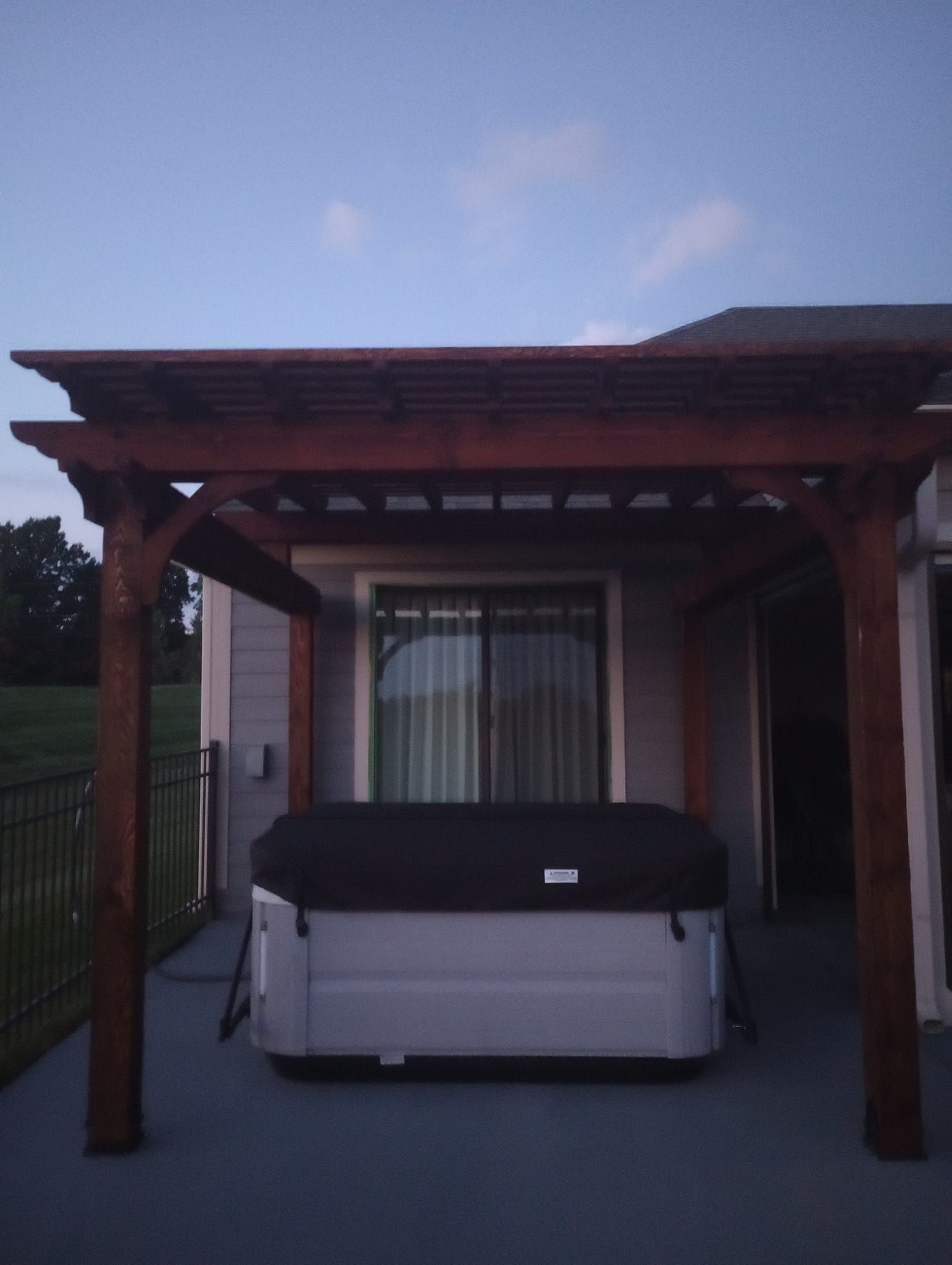 A hot tub under a pergola on a patio