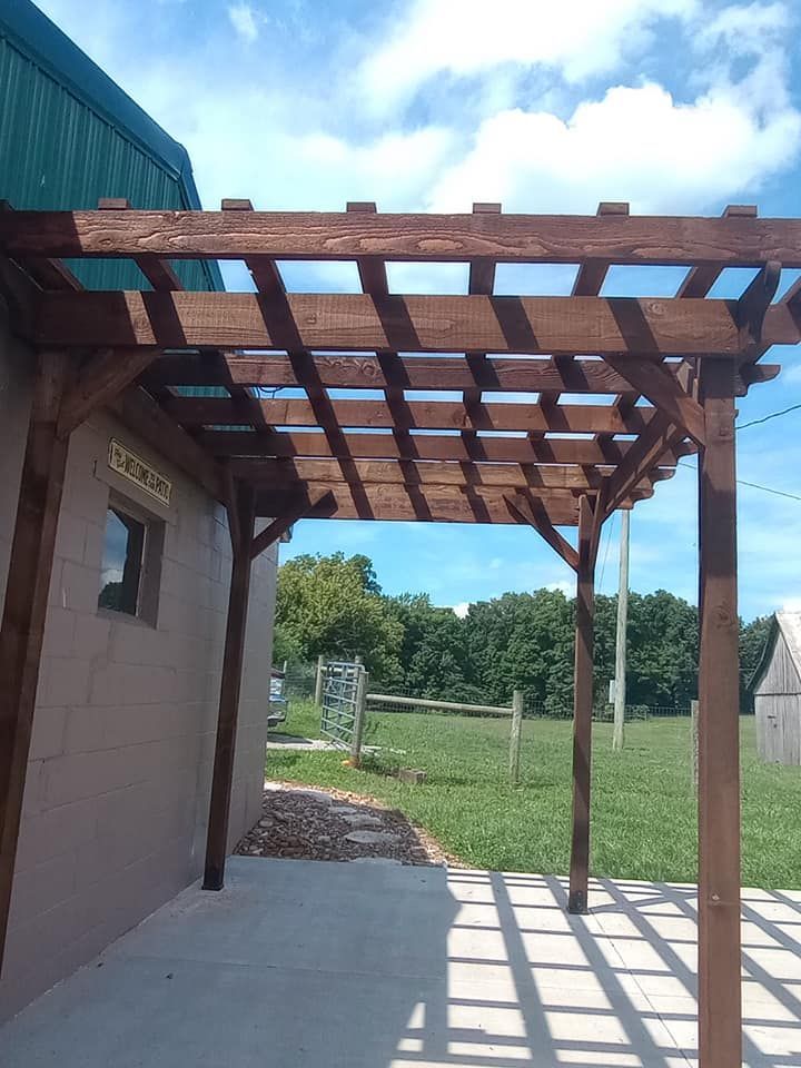 A wooden pergola is attached to the side of a building