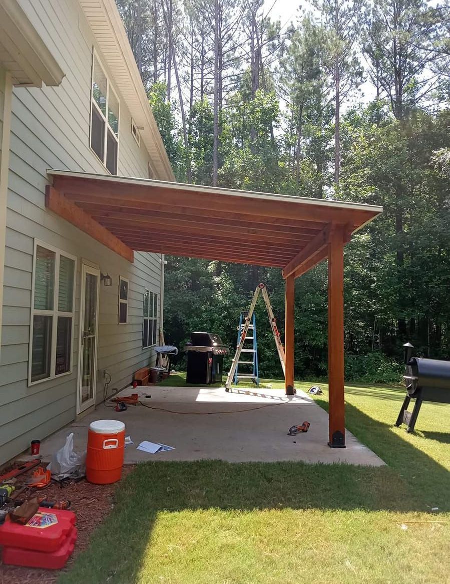 A wooden pergola is being built in the backyard of a house.