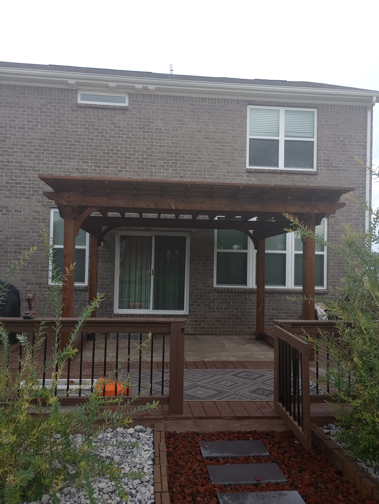 A brick house with a wooden pergola on the front porch