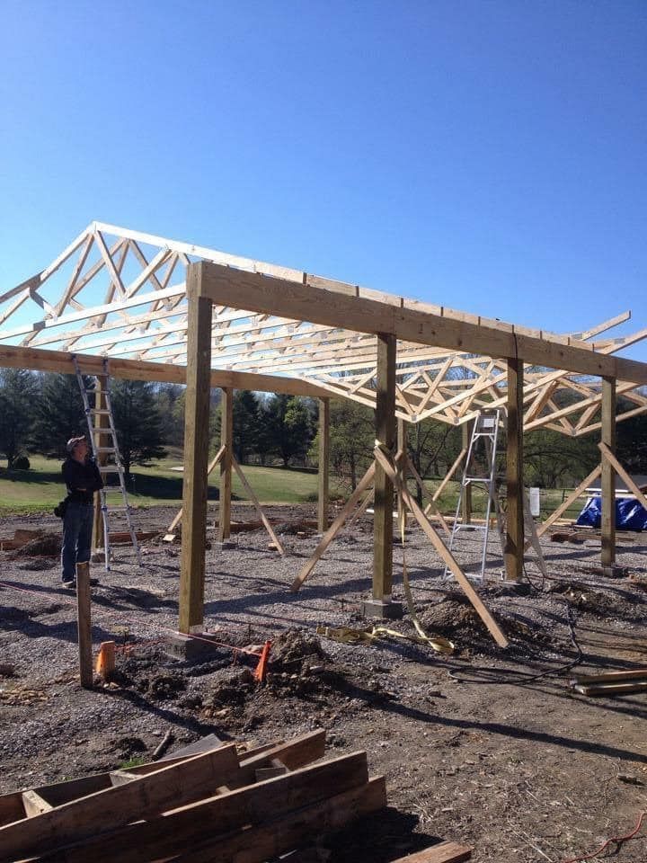 A man is standing in front of a wooden structure under construction
