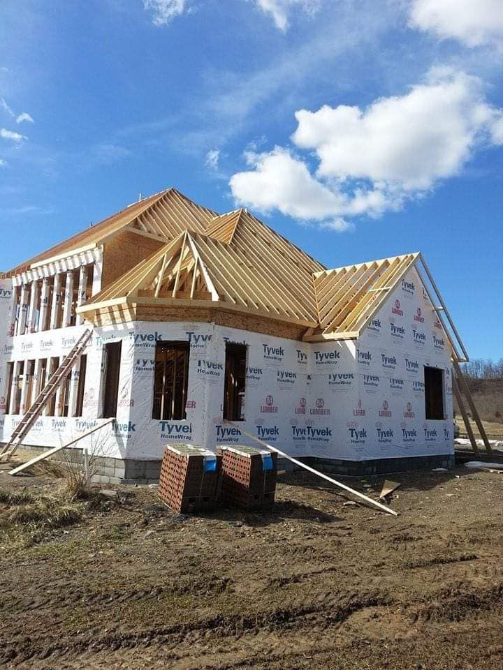 A house is being built in a field with a blue sky in the background.
