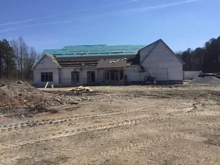 A large house is being built in the middle of a dirt field.