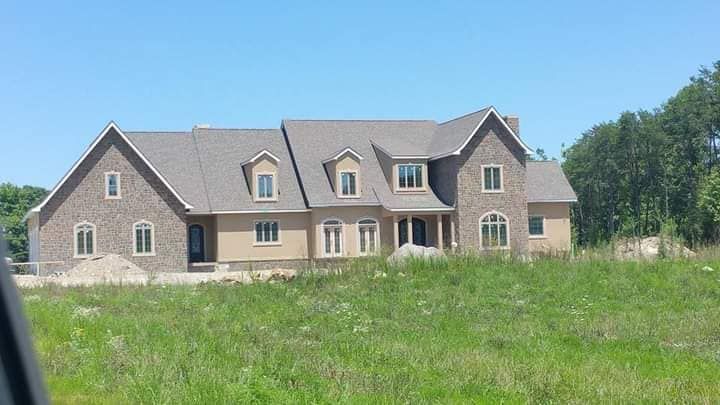 A large house is sitting in the middle of a grassy field.