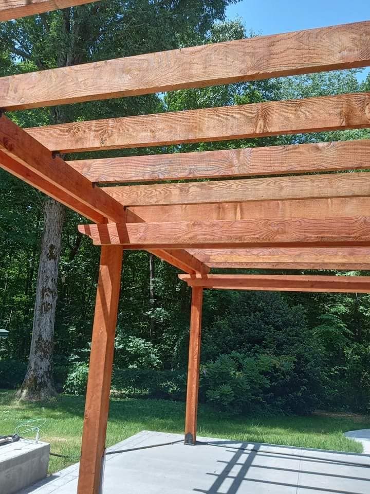 A wooden pergola is sitting on top of a concrete patio.