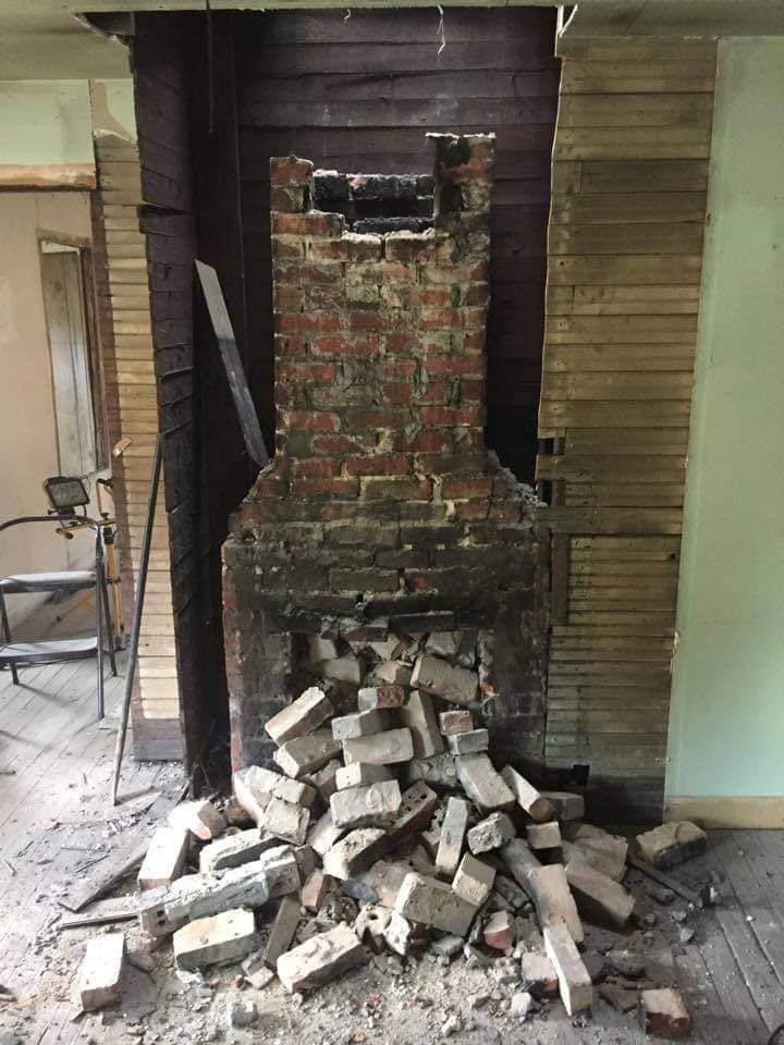 A pile of bricks is sitting in front of a brick fireplace.