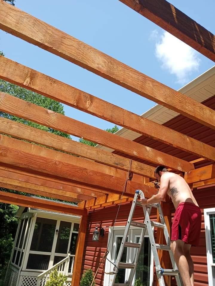 A man standing on a ladder working on a wooden structure