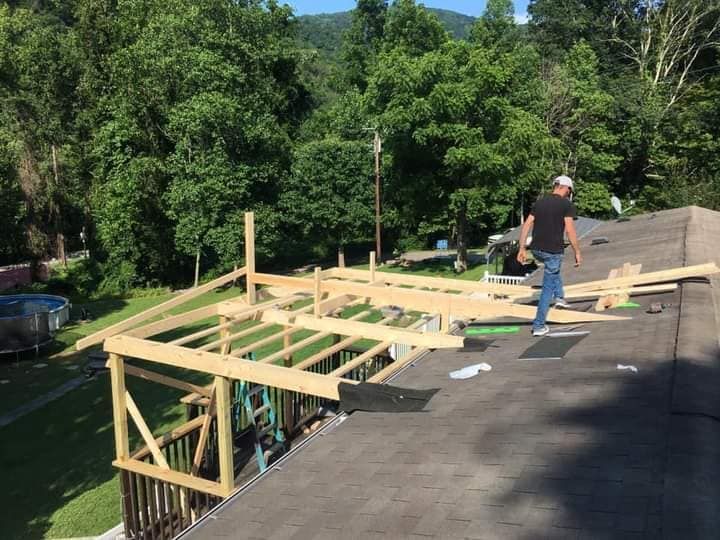 A man is standing on top of a roof with wooden beams.