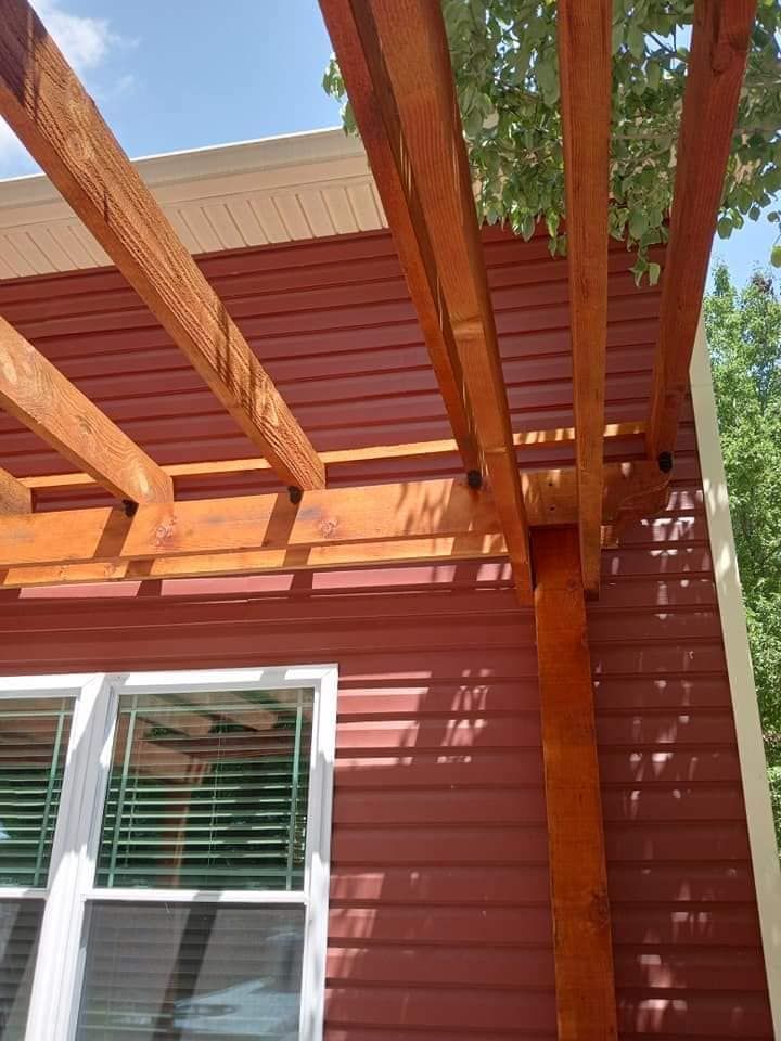 A red house with a wooden pergola on top of it.