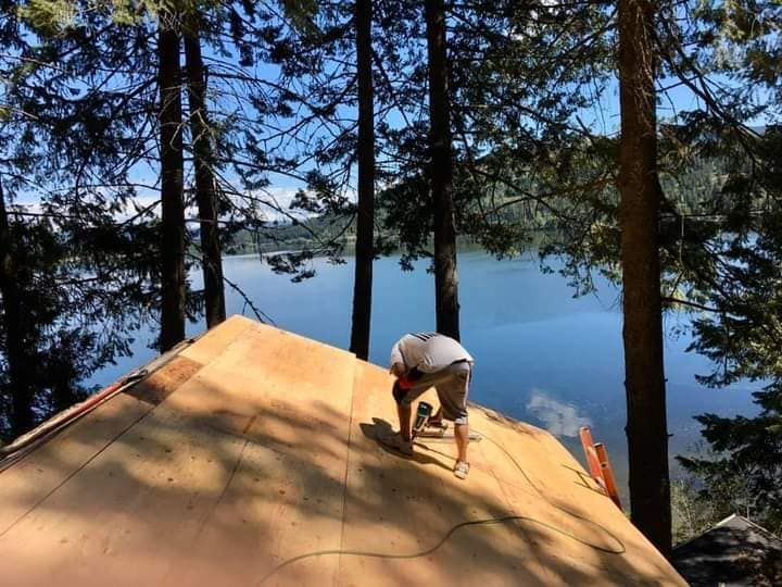 A man is working on a roof overlooking a lake