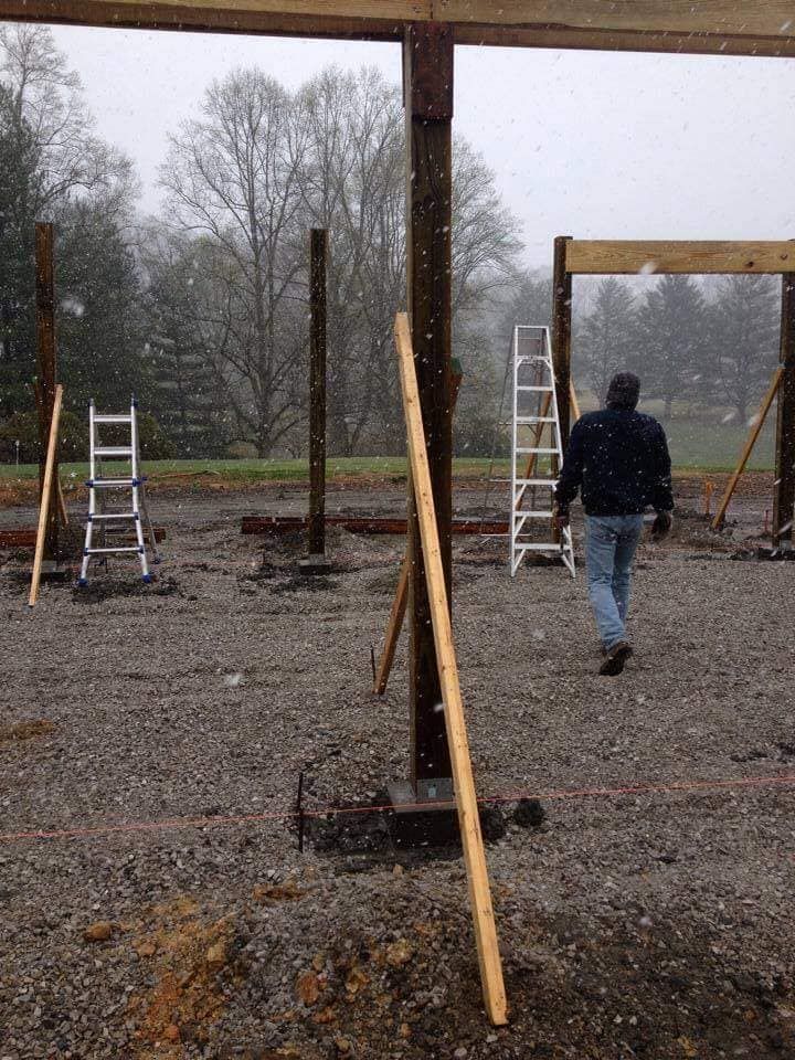 A man is walking through a construction site with a ladder in the background