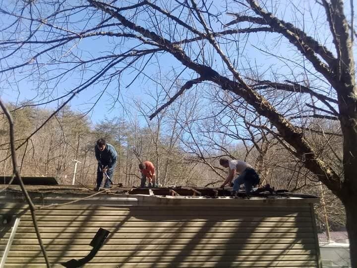 A group of people are working on the roof of a house