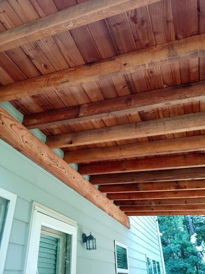 The ceiling of a porch with wooden beams on a house.