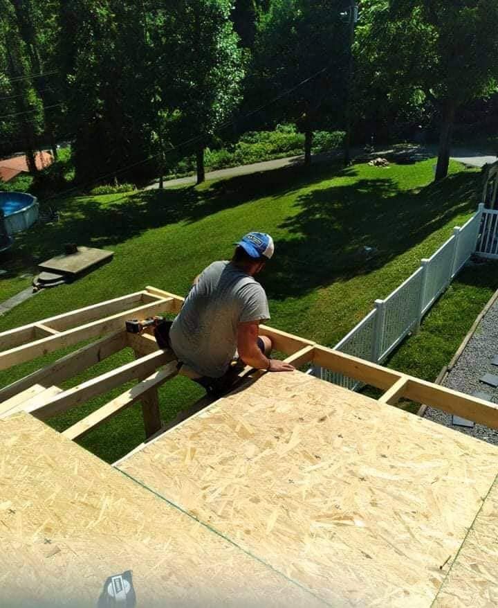 A man is sitting on top of a wooden structure.