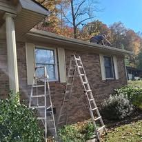 A man is working on the roof of a house with a ladder.