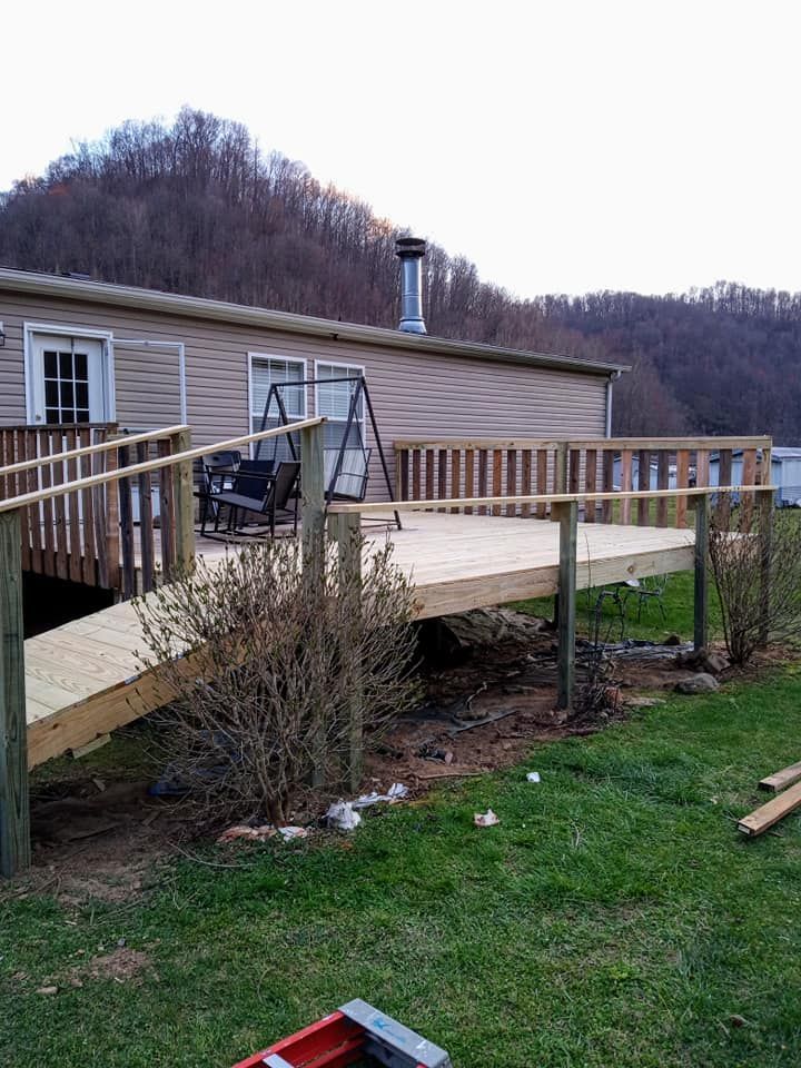 A mobile home with a wooden deck and ramp in front of it.