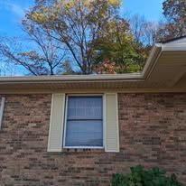 A brick house with a window and shutters on it.