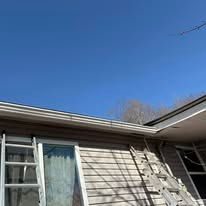 A house with a ladder on the side of it and a blue sky in the background.