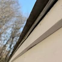 A close up of a gutter on the side of a house.