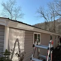 A ladder is sitting on the side of a house next to a roof.