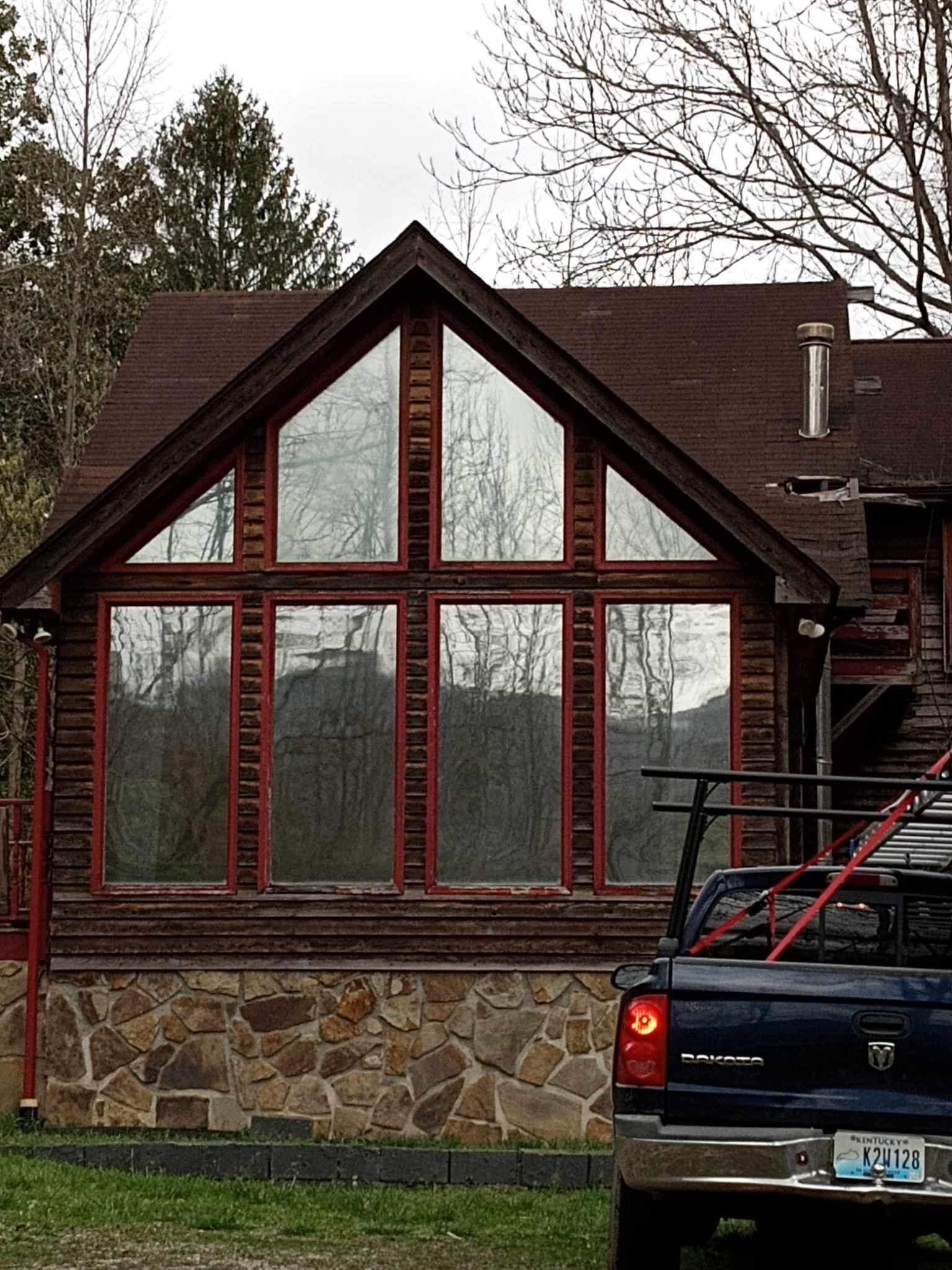 A truck is parked in front of a house with a lot of windows.