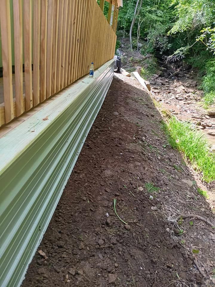 A man is standing on a dirt hill next to a wooden fence.