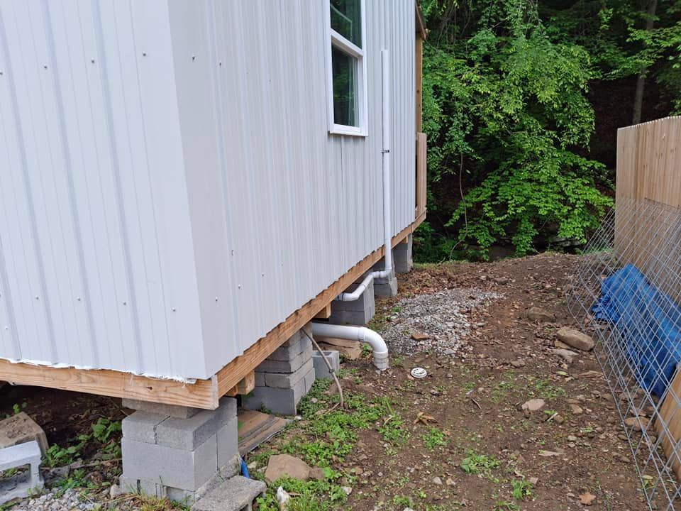 A white building is sitting on top of concrete blocks next to a fence.